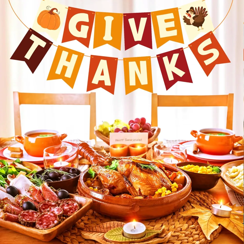 A laid Thanksgiving table with a roast turkey, orange napkins and a GIVE THANKS banner behind it